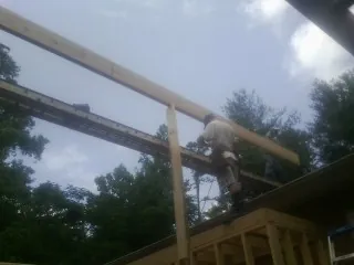 Carpenter setting a ridge beam over a new addition frame — Ice Dam Removal by Roofing Brothers in Belle Rose