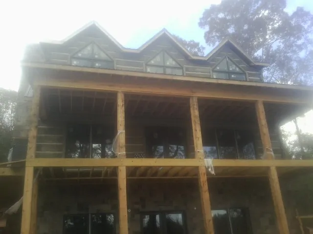 Dormers and porch framing on a large log home under construction — Roof Coating work by our crew in Belle Rose