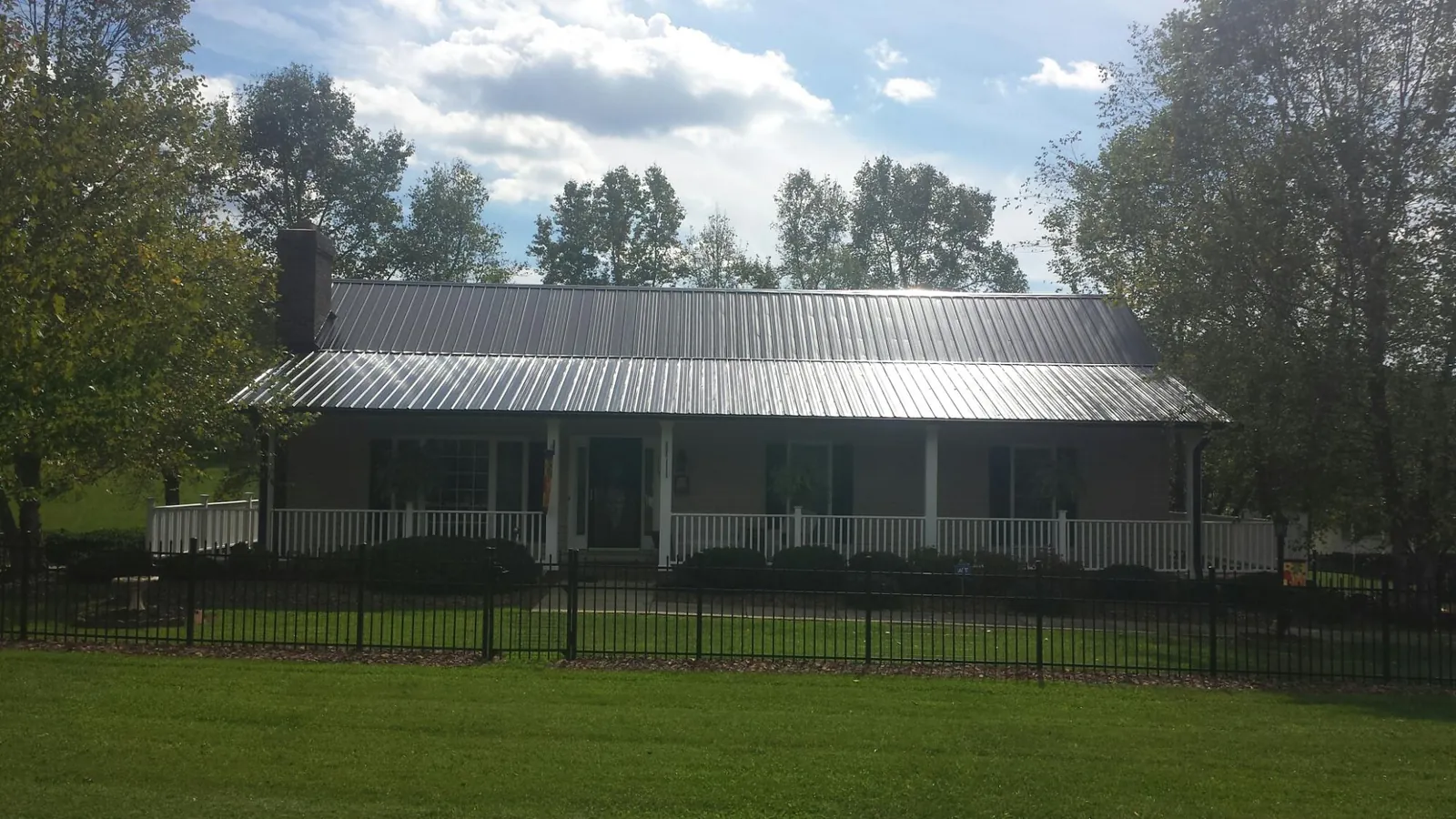 Gray metal roof on a brick ranch with a full width front porch — Gutter Guard Installation work by our crew in Belle Rose