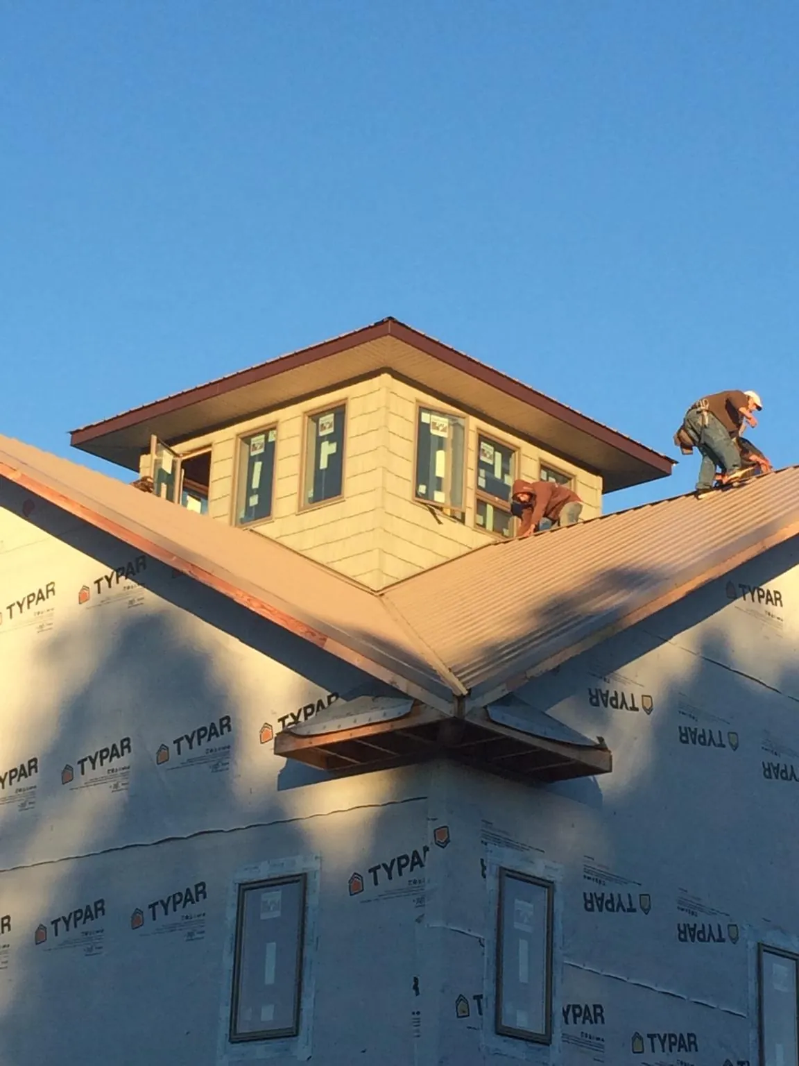Roofers working around a rooftop cupola on a new metal roof at sunset — Roof Waterproofing in Belle Rose by Roofing Brothers